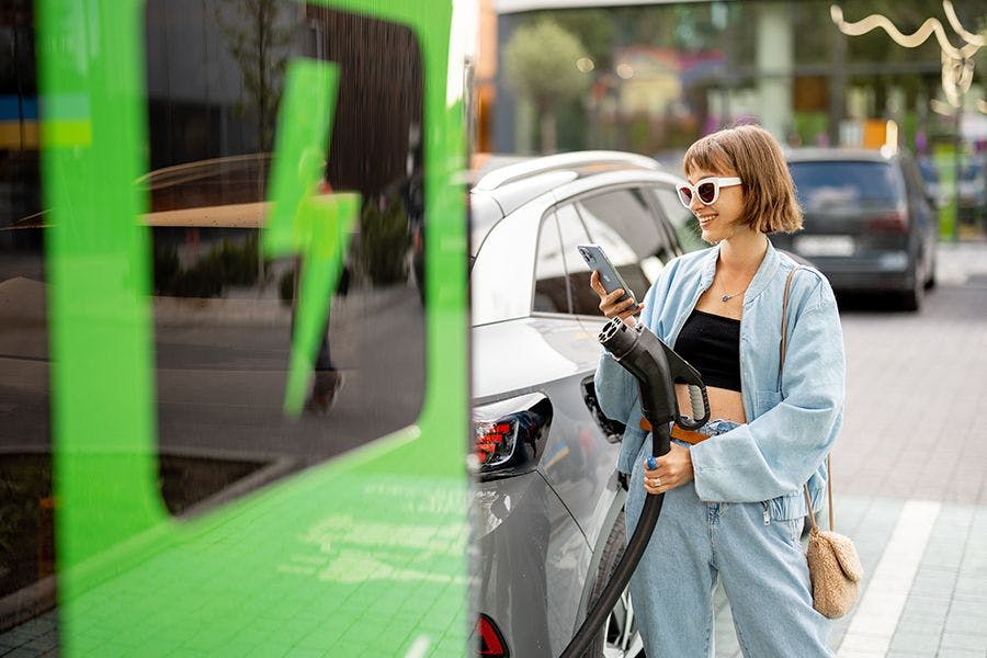 Vrouw is haar elektrische auto aan het opladen die ze met subsidie heeft gekocht